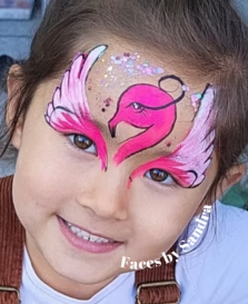 Young girl with flamingo face paint on her forehead in pink tones