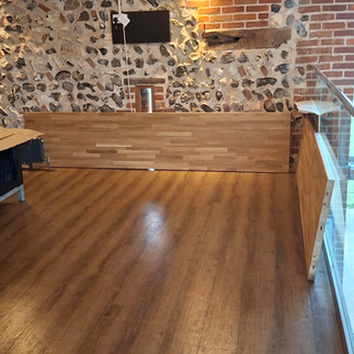 Wood effect oak floor with oak bar surfaces propped against the walls ready to be installed.