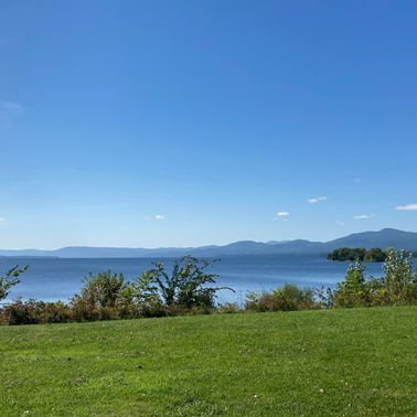 A sunny photo of a large lake with mountains in the background