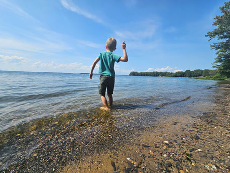 A young boy skipping rocks at a lake on a sunny day