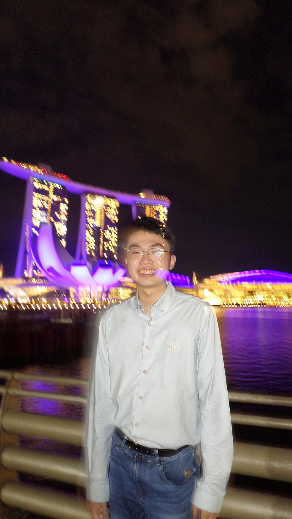 Ron stands in front of the Marina Bay night skyline