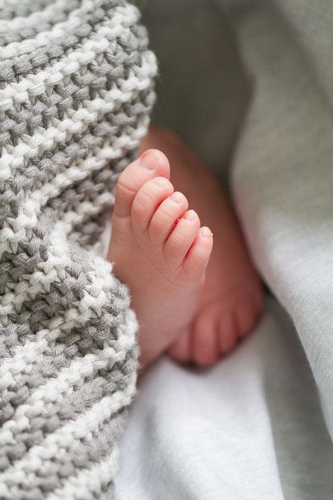 a baby's foot is laying under a knitted blanket
