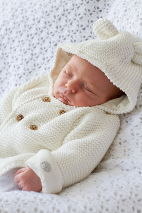 a baby is wearing a white sweater with a hood