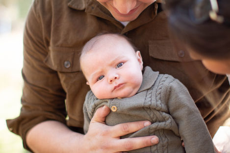 baby boy on dads lap wearing green outfit