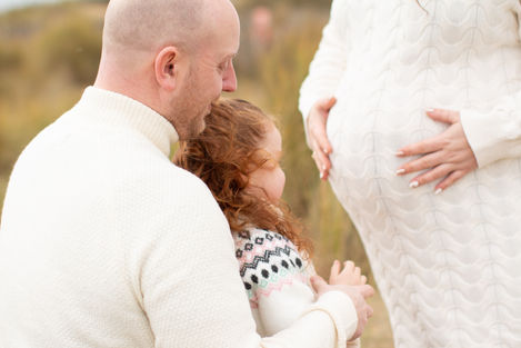 a man and a little girl are looking at a pregnant woman 's belly