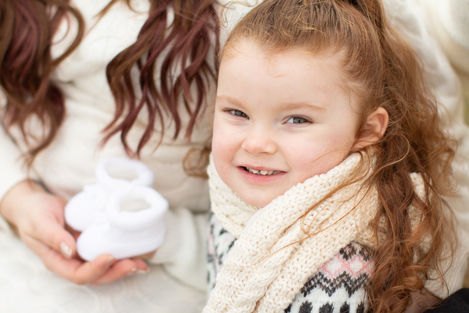 a little girl with a scarf around her neck smiles for the camera