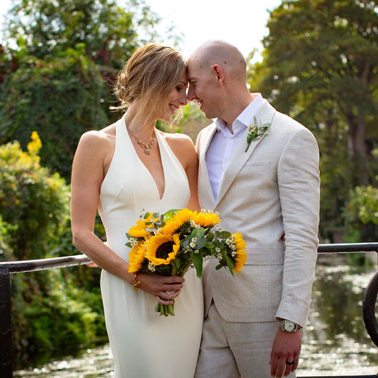 Bride and groom embracing with sunflowers bouquet.
