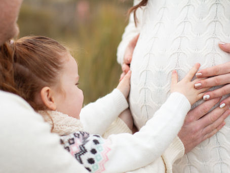 young girl holding pregnant mums tummy