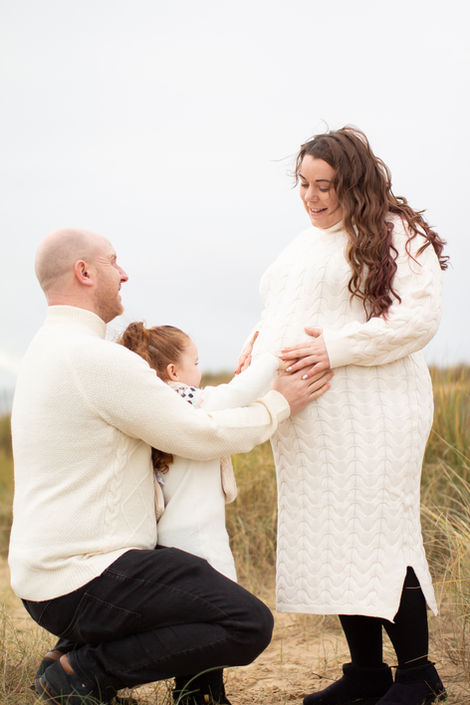 a pregnant woman is being held by a man and a little girl