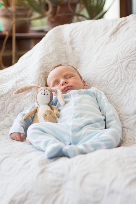 a baby in a blue and white striped outfit is sleeping with a stuffed rabbit