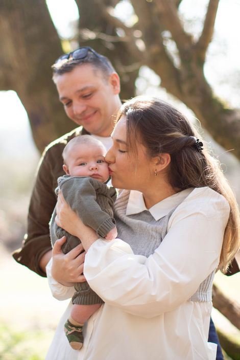 mum kissing baby son on cheek while dad looks on