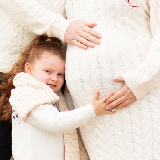 a little girl is hugging a pregnant woman 's belly