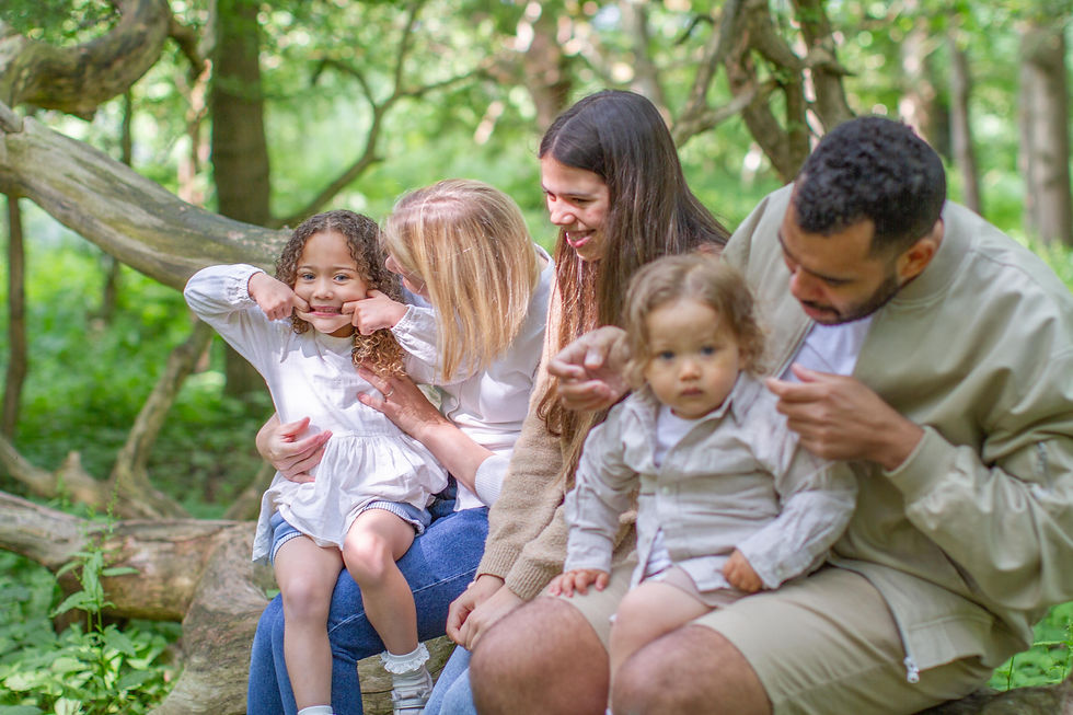 Family of 5 sitting on a log in the woods
