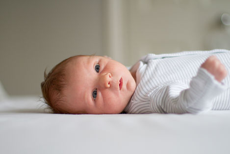 a baby with blue eyes is laying on a bed
