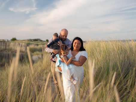 Family walking through sand dunes at sunset