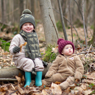 Boy sits near to baby sister in the forest holding a crisp brown leaf