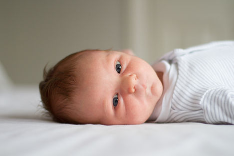 a baby is laying on a bed and looking at the camera