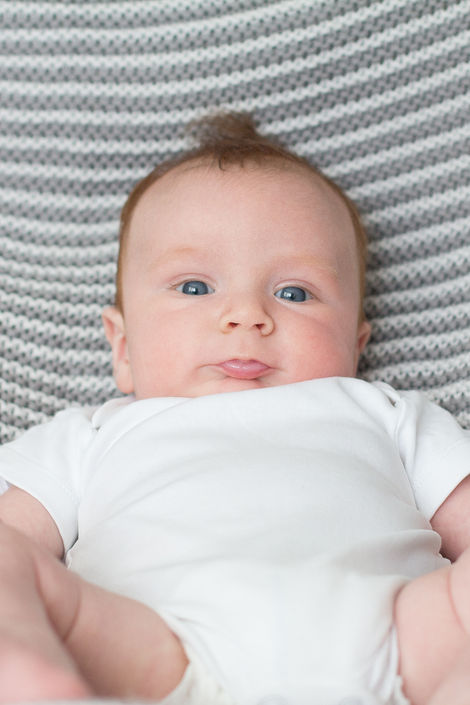 a baby with blue eyes is laying on a blanket