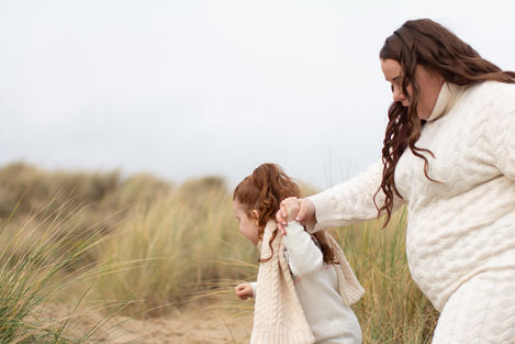 a woman in a white sweater is holding a little girl 's hand