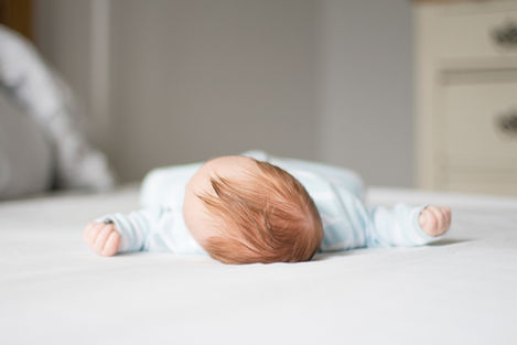 a baby is laying on its back on a bed