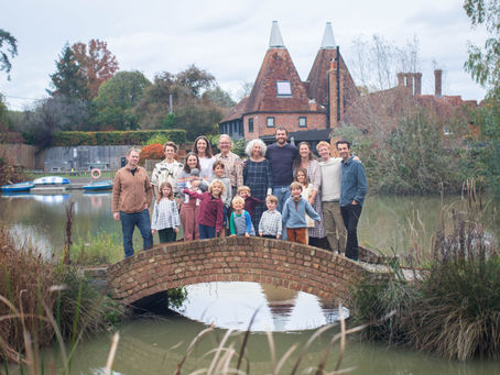 large family standing together on a bridge over pond