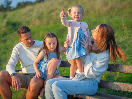 family of four sit on bench in the countryside 