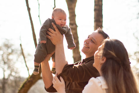 dad lifts baby boy into the air while mum looks on