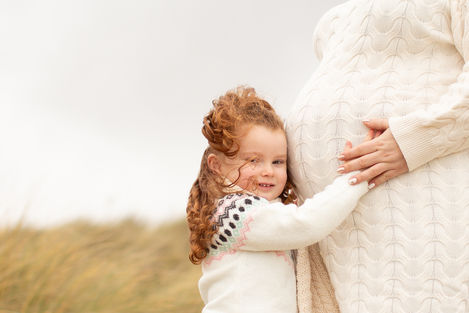 a little girl is hugging a pregnant woman's belly