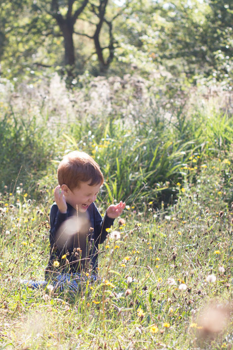 a young boy is sitting and laughing in a field of flowers