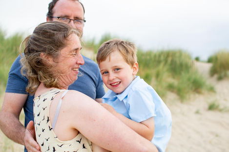 Family smiling together at the beach.