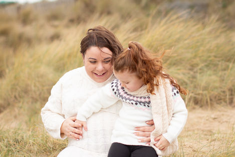 a woman in a white sweater is holding a little girl