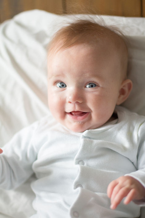 a baby with blue eyes is smiling and looking at the camera