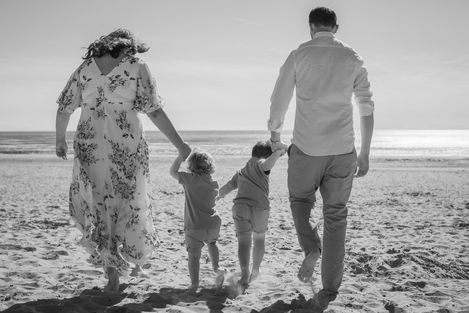 family walk together away from camera on beach