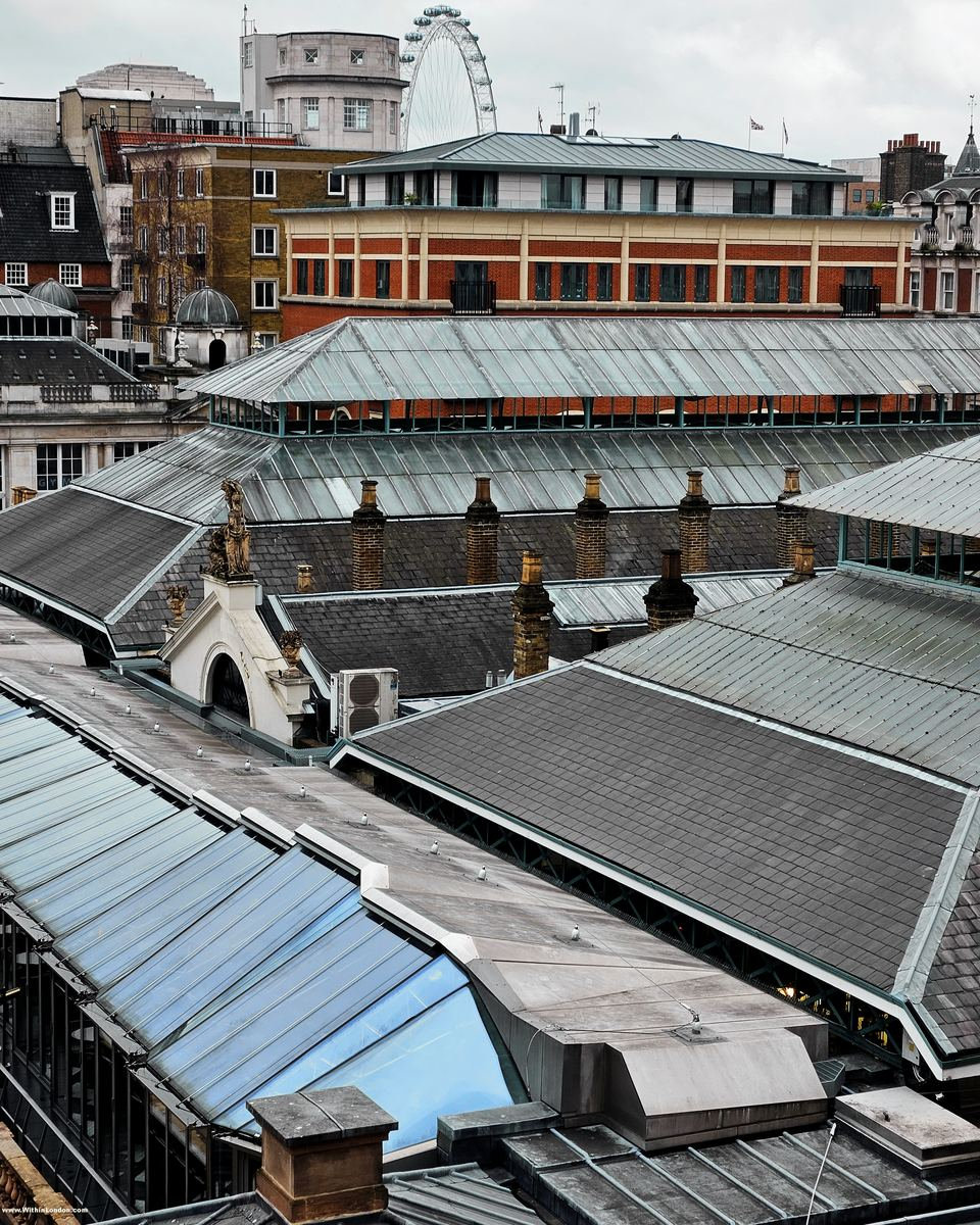 Glass and iron roofs of the Covent Garden market building from above, with the London Eye rising behind