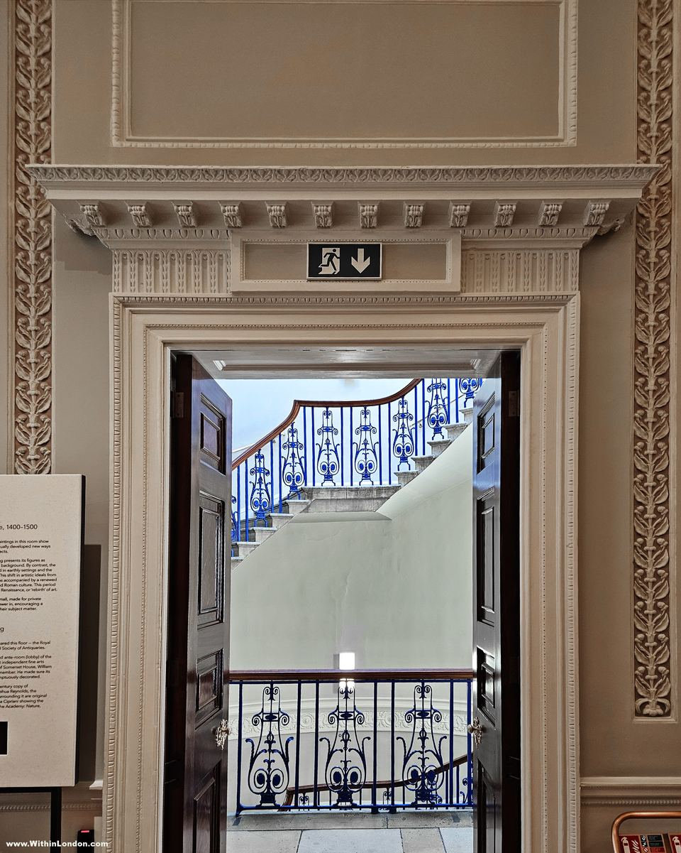 Classical stone doorway opening onto a staircase with blue-painted iron balustrades
