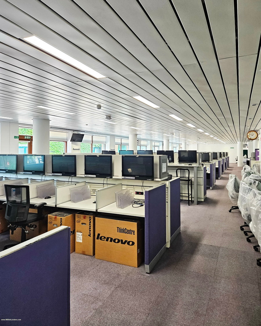 Empty open-plan media centre office with rows of desks and computer screens