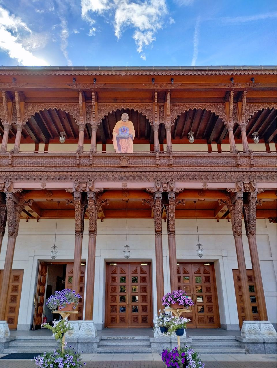 The carved dark wooden front of the Haveli cultural centre, with balconies, arches and brackets above three wooden doors