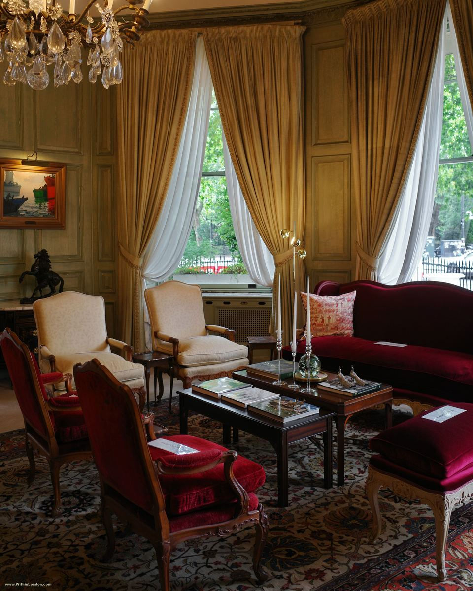 The canted bay window of the Green Room at 49 Belgrave Square, hung with gold curtains and looking out onto the trees of Belgrave Square