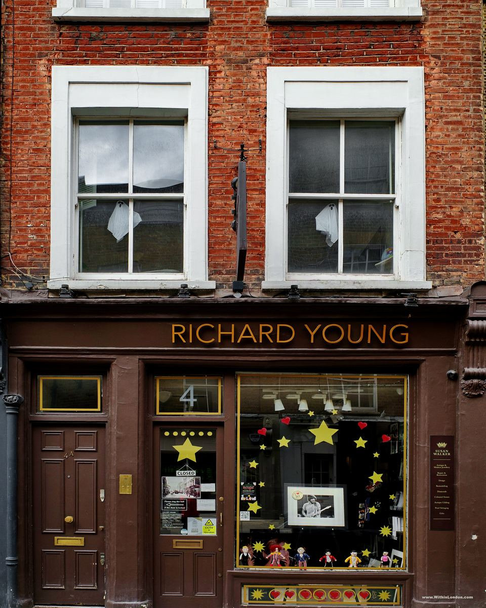 The dark brown shopfront of the Richard Young Gallery on Holland Street, with yellow stars and red hearts stuck across the window