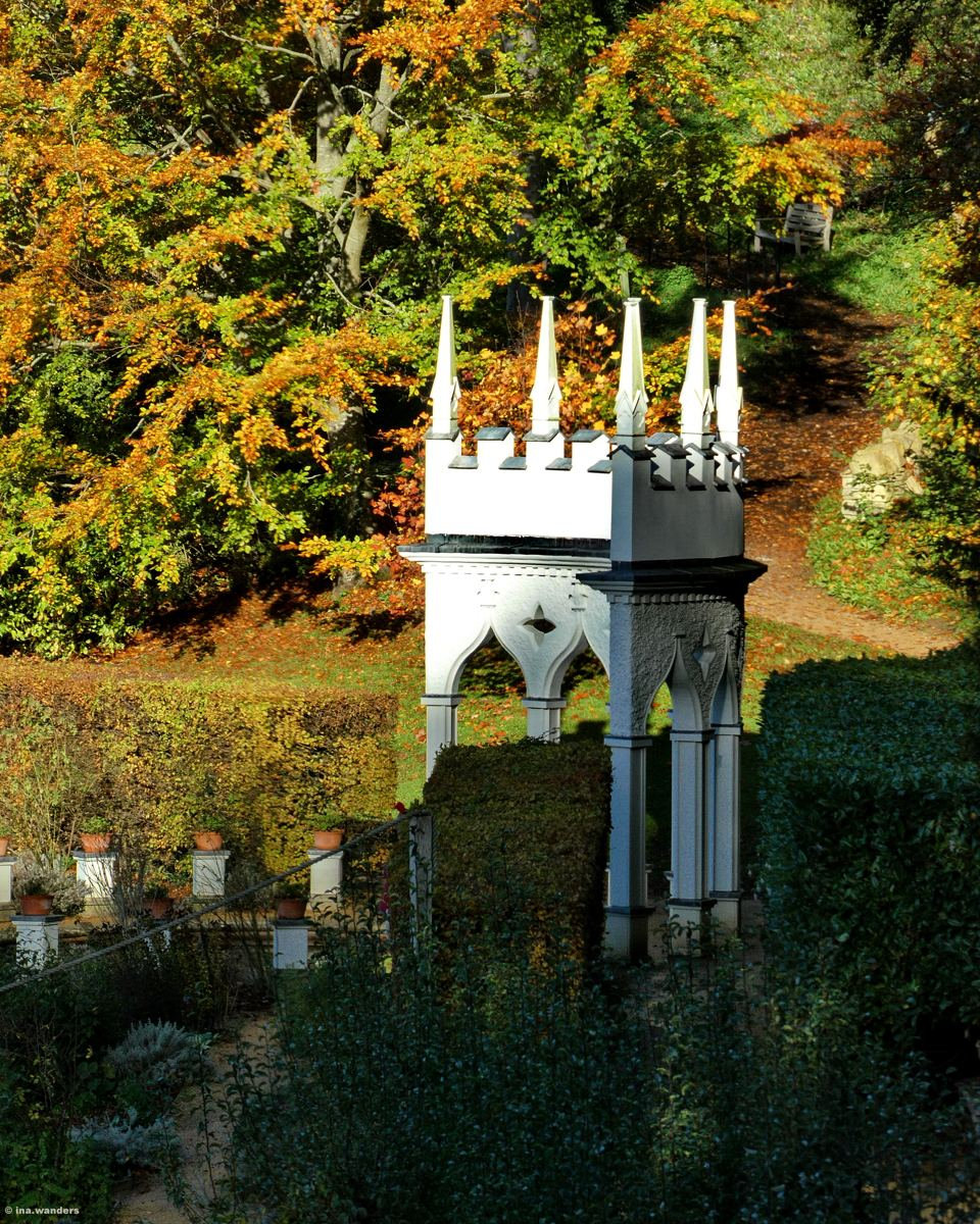 Close view of the white Gothic alcove with tall pinnacles and pointed arches, framed by yellow and orange leaves