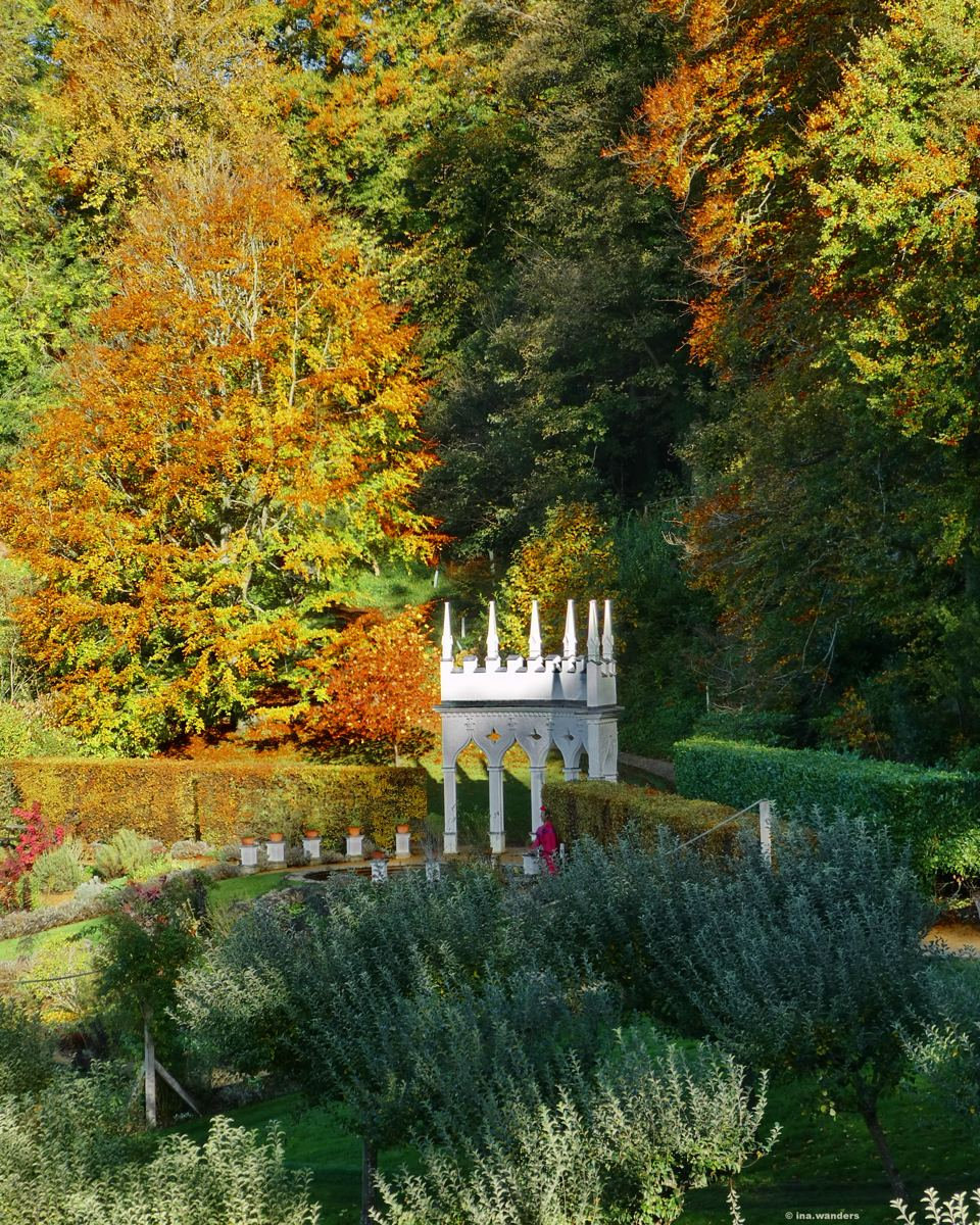 White Gothic alcove with pinnacles among autumn beech trees at the edge of Painswick Rococo Garden