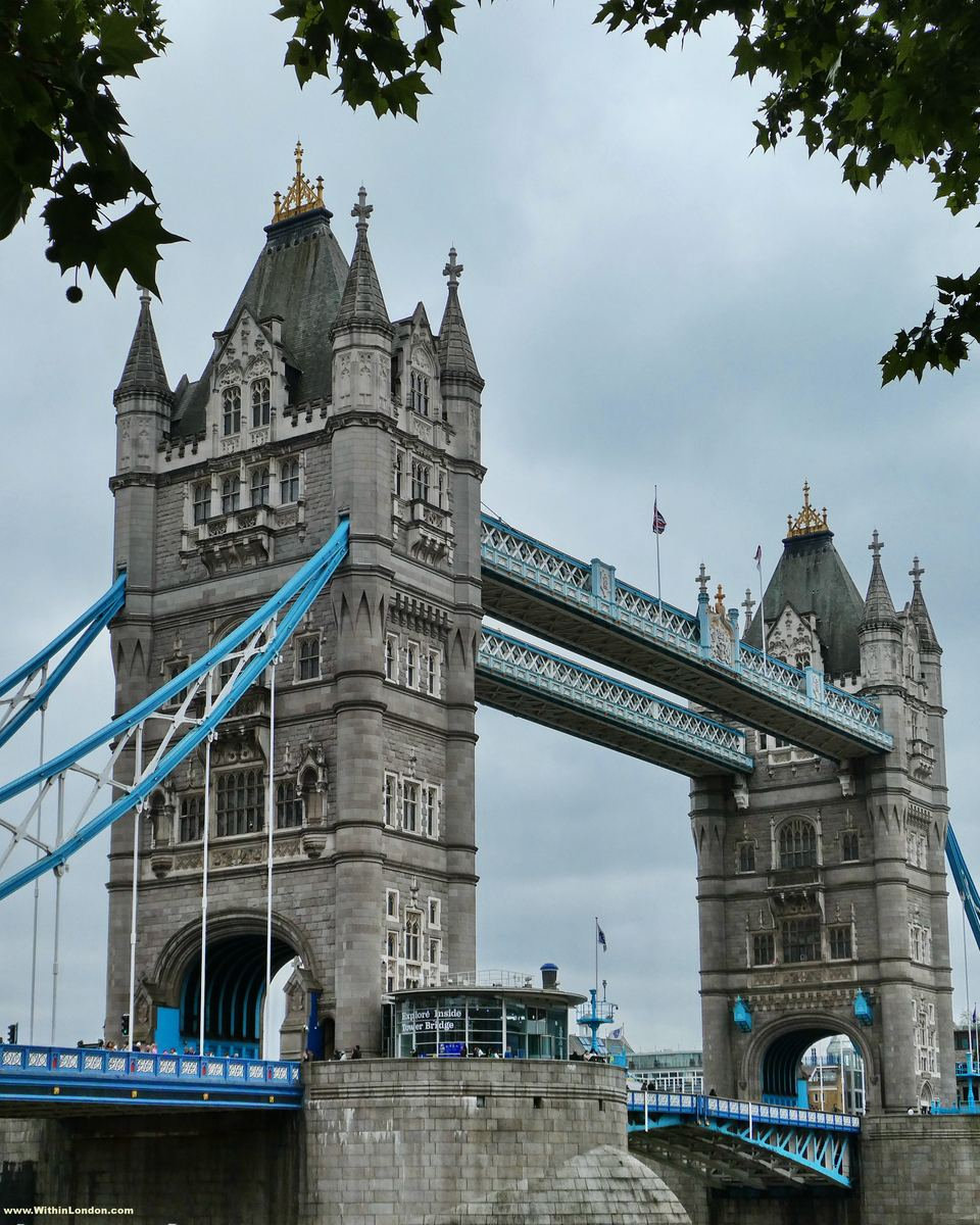 Tower Bridge's two stone towers and blue-painted girders above the Thames on a summer evening