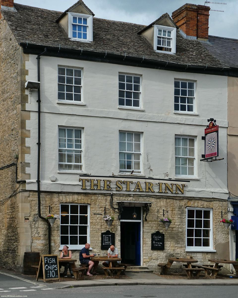 The Star Inn on Market Place in Woodstock, a three-storey stone and white-painted pub with a hanging sign, blackboard and drinkers at tables outside