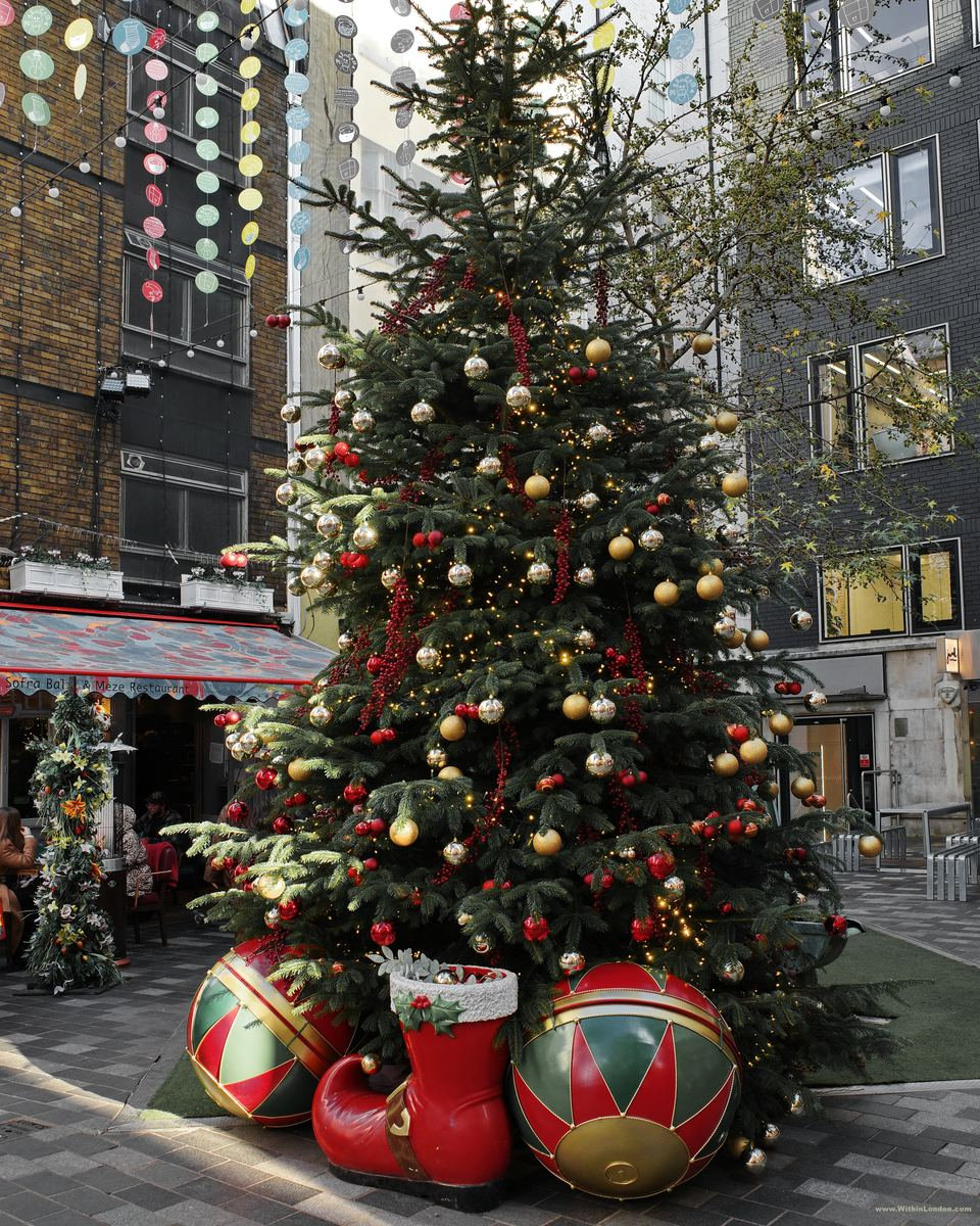 A decorated Christmas tree with giant red and green baubles and a Santa boot at its base in St Christopher's Place