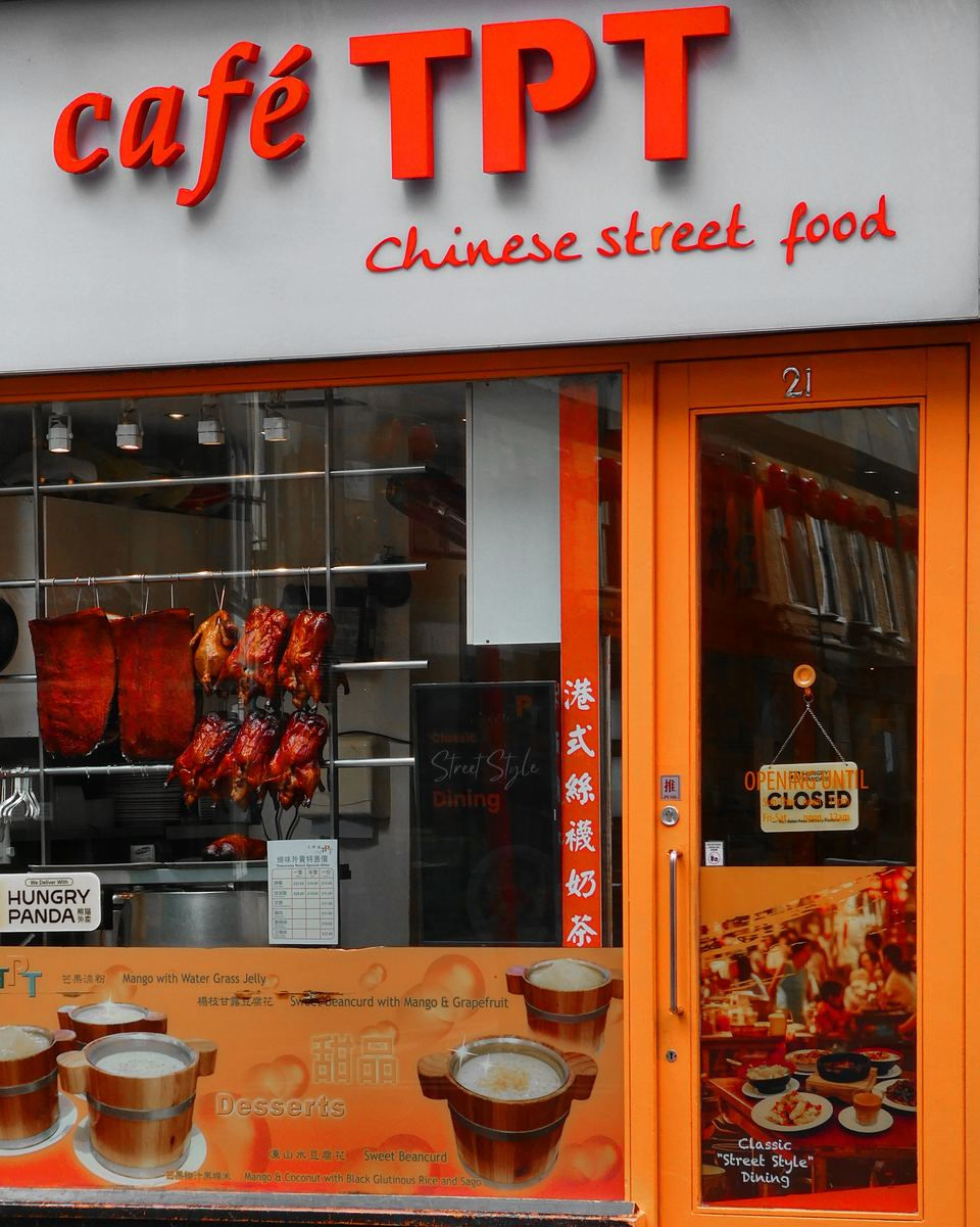 The orange frontage of Cafe TPT on Wardour Street, with roast ducks hanging in the window under a Chinese street food sign
