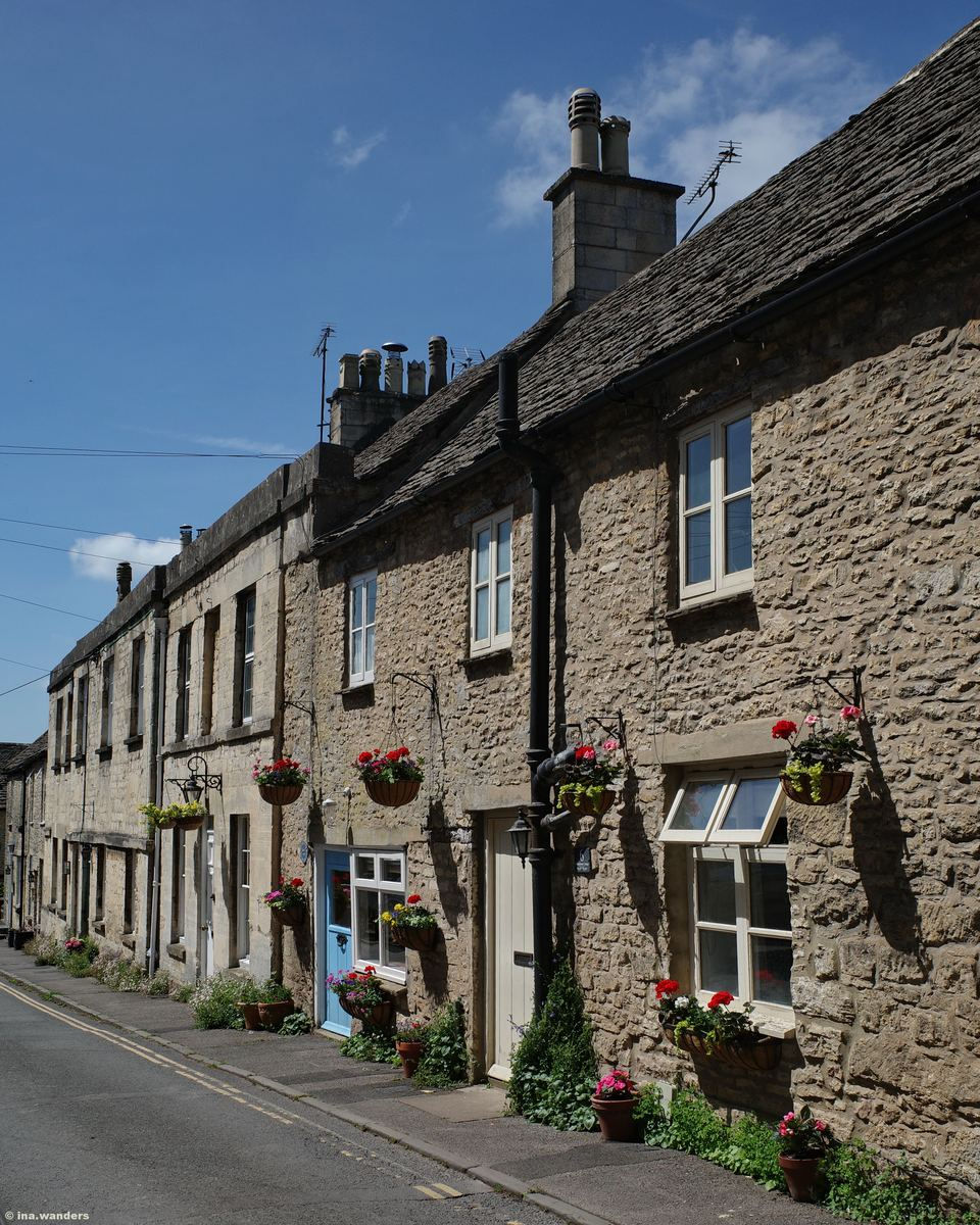 Cottages along Minchinhampton's high street decorated with hanging baskets