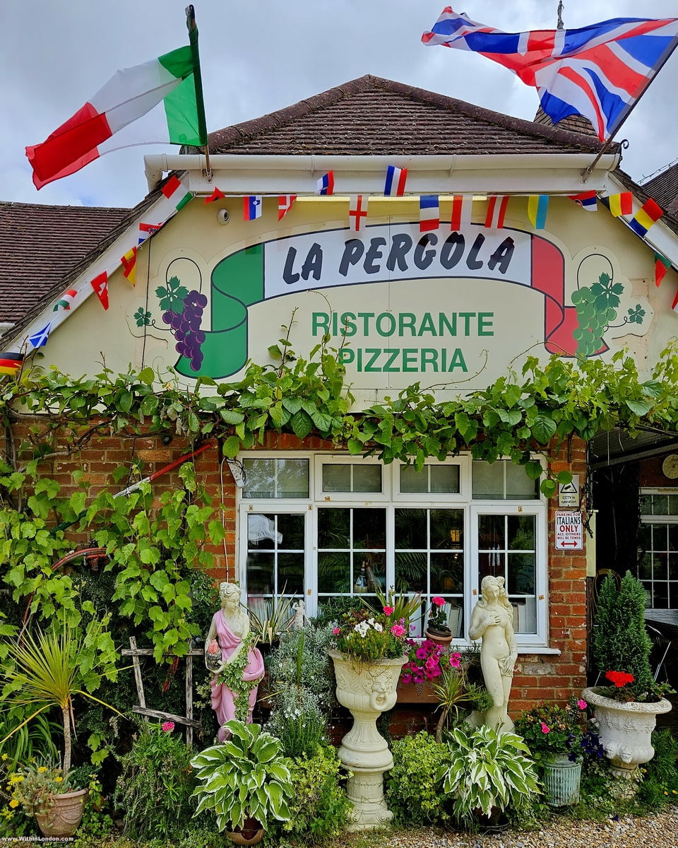 The flower-covered front of La Pergola, an Italian restaurant in Lyndhurst, with bunting above the sign