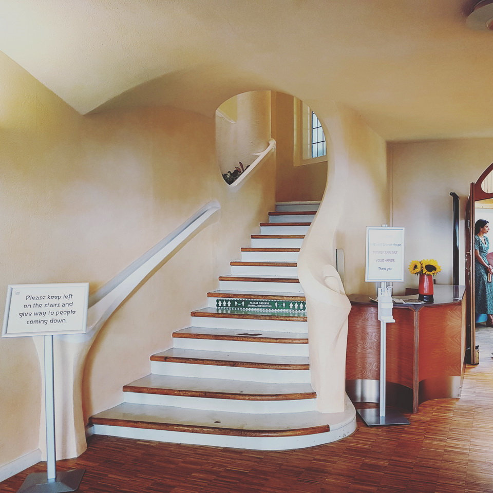 A curving Expressionist staircase with rounded, organic concrete forms and soft painted walls