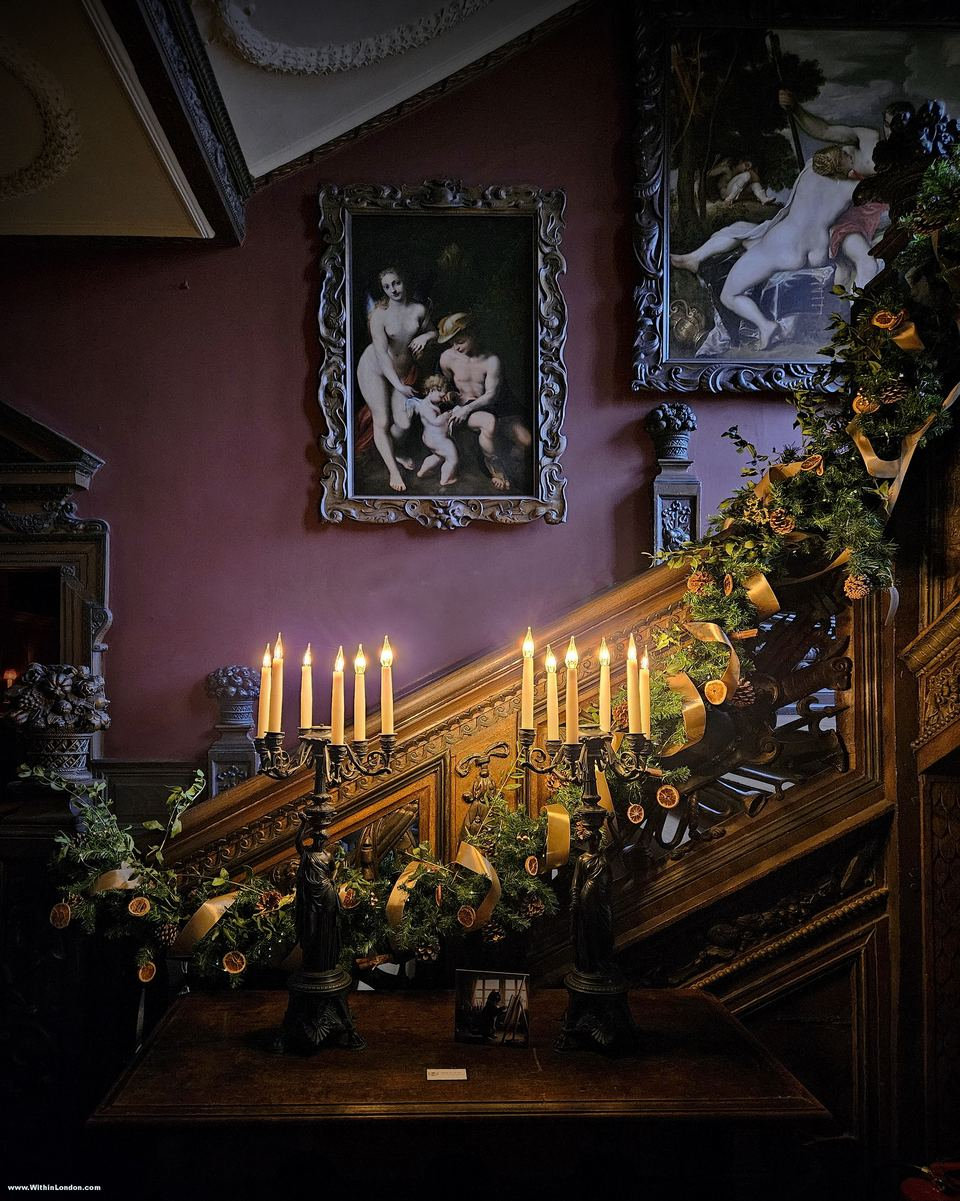 A dark carved wooden staircase dressed with candelabras and green garlands for Christmas