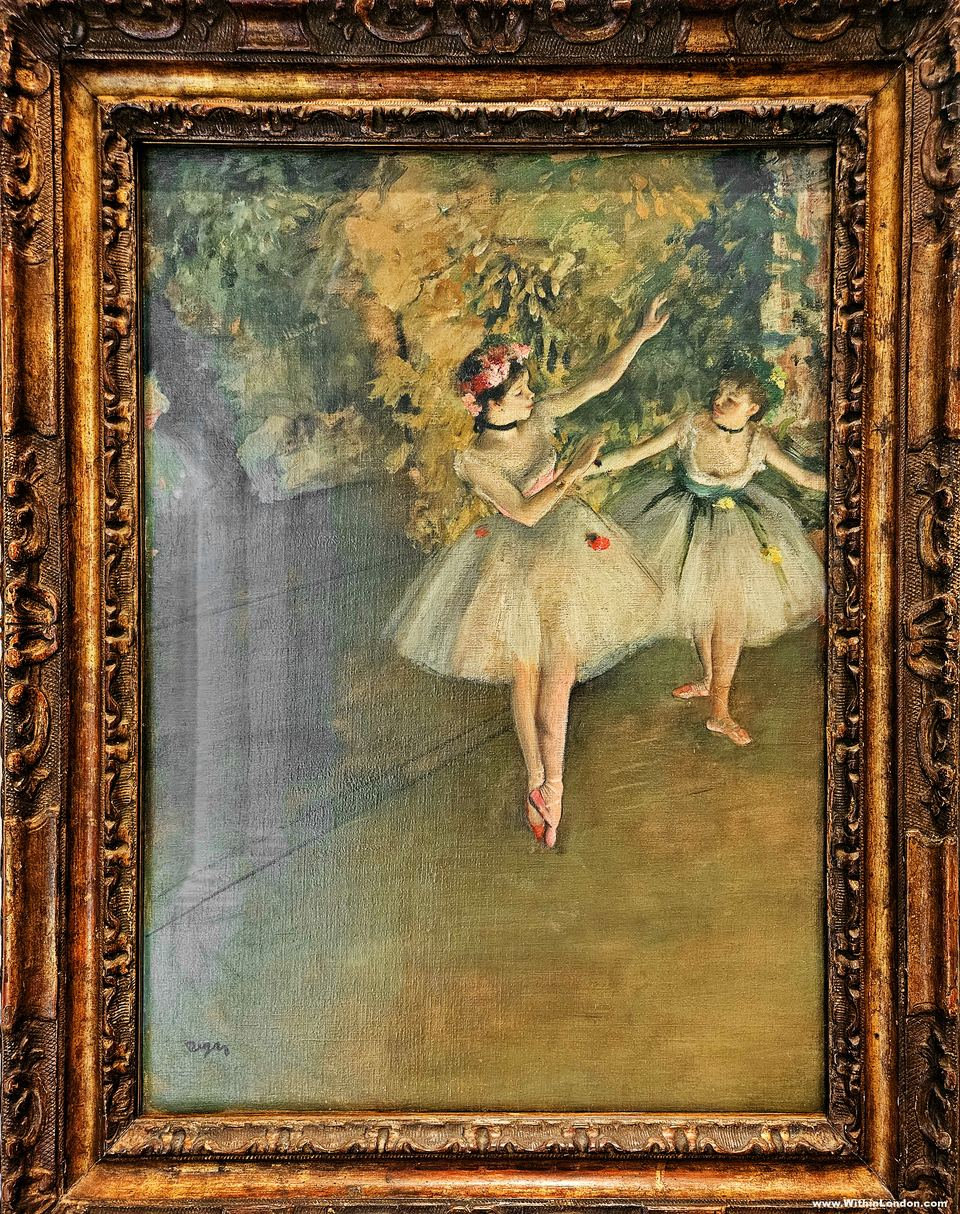 Degas painting of two ballet dancers in white tutus on a green-toned stage, in a carved gold frame